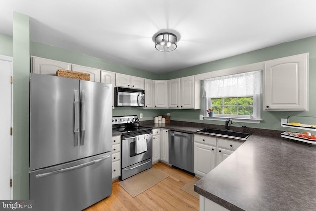  - kitchen with stainless steel appliances, dark countertops, light wood finished floors, and white cabinets