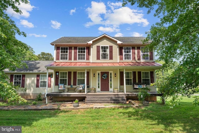  - colonial-style house featuring a porch, a front lawn, and a standing seam roof