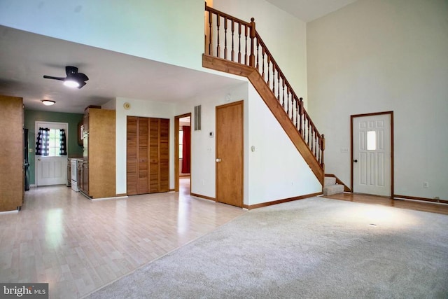 107 Birchside Cir, Locust Grove, VA 22508 - unfurnished living room with baseboards, stairs, ceiling fan, a high ceiling, and light wood-type flooring