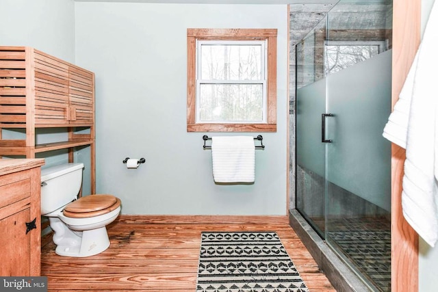 bathroom featuring hardwood / wood-style flooring, toilet, and a shower with door