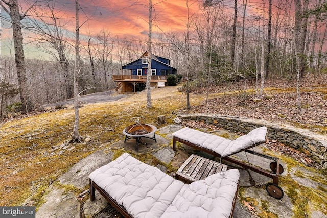 yard at dusk with a deck and an outdoor fire pit