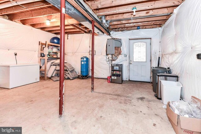 basement with white refrigerator and electric panel