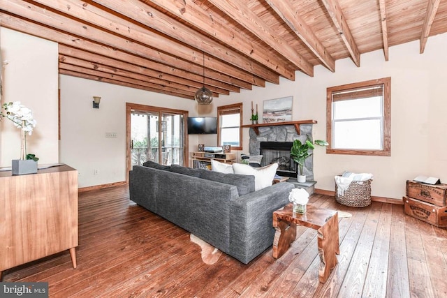 living room with hardwood / wood-style flooring, a stone fireplace, wooden ceiling, and beam ceiling