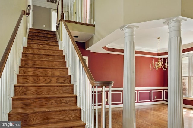 stairway with a notable chandelier, ornamental molding, visible vents, wood finished floors, and ornate columns