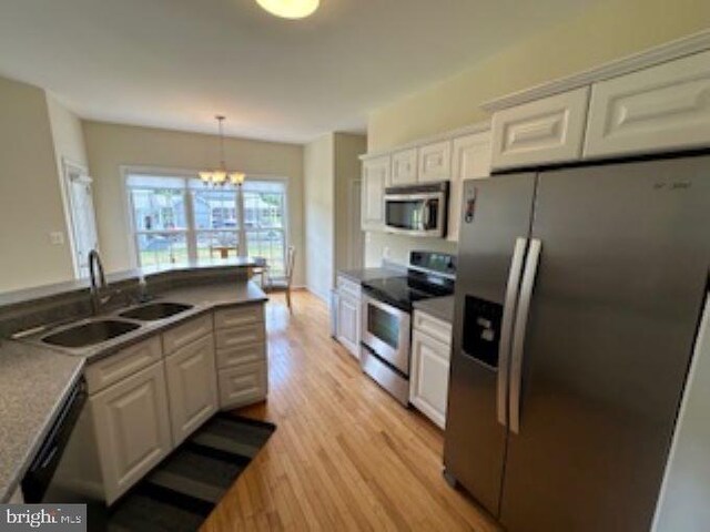 kitchen featuring hanging light fixtures, appliances with stainless steel finishes, sink, and white cabinets