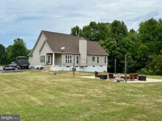 rear view of house with a fire pit and a lawn