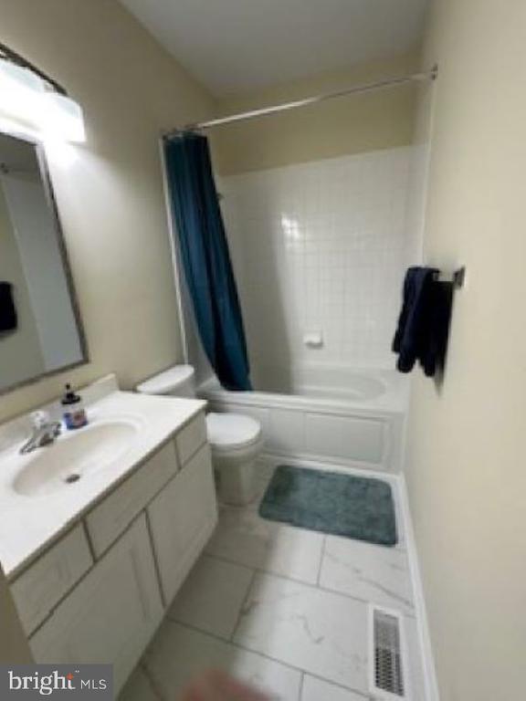 full bathroom featuring vanity, shower / tub combo, and toilet