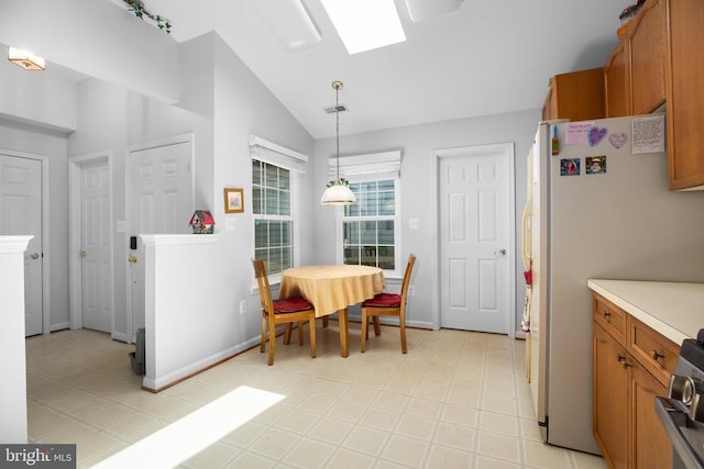 11611 Hampshire Ct, Fredericksburg, VA 22407 - kitchen with vaulted ceiling, brown cabinetry, freestanding refrigerator, pendant lighting, and a skylight