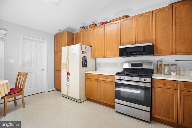 11611 Hampshire Ct, Fredericksburg, VA 22407 - kitchen with appliances with stainless steel finishes, light countertops, brown cabinets, lofted ceiling, and light floors
