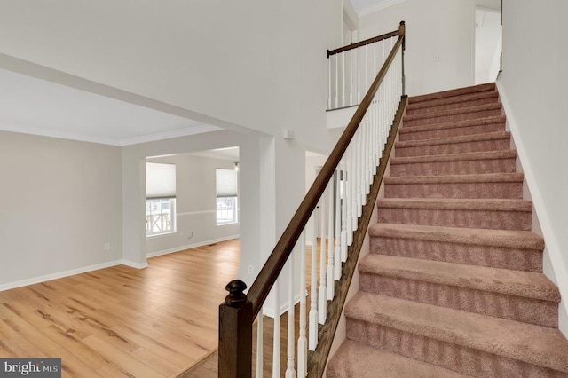 staircase with ornamental molding and hardwood / wood-style floors