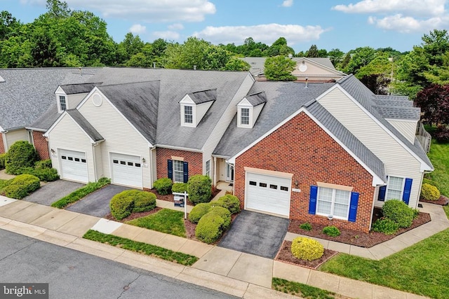 view of front of home featuring brick siding, driveway, and a shingled roof