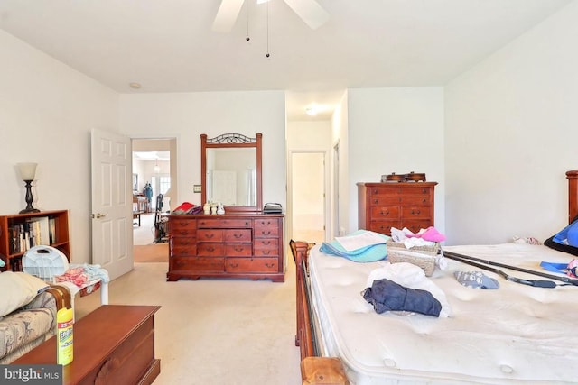 bedroom with light colored carpet, a ceiling fan, and ensuite bath