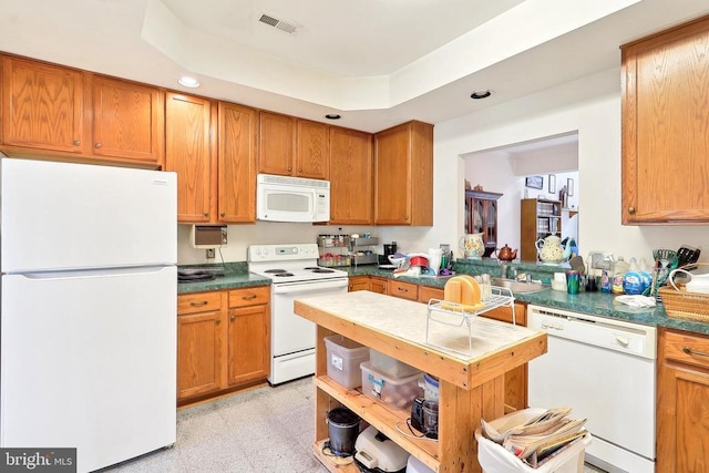 kitchen featuring white appliances, recessed lighting, brown cabinets, and dark countertops