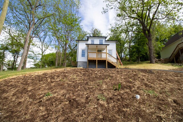 back of property with stairway and a porch