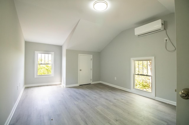 bonus room featuring an AC wall unit, vaulted ceiling, plenty of natural light, wood finished floors, and baseboards