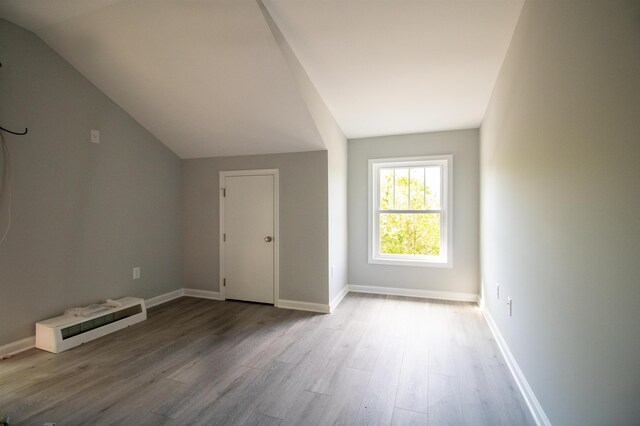 additional living space with lofted ceiling, wood finished floors, and baseboards