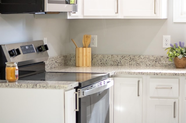 kitchen with electric stove, white cabinets, and light stone counters