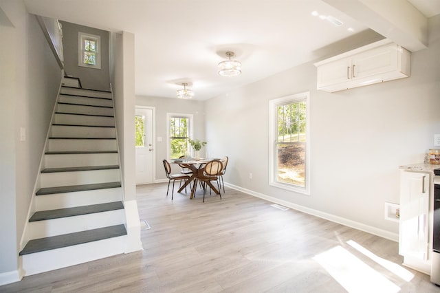 dining area with stairway, light wood-type flooring, plenty of natural light, and baseboards
