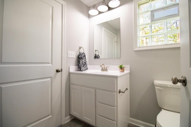 half bath featuring toilet, vanity, and baseboards