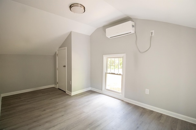 additional living space featuring a wall unit AC, lofted ceiling, dark wood-type flooring, and baseboards