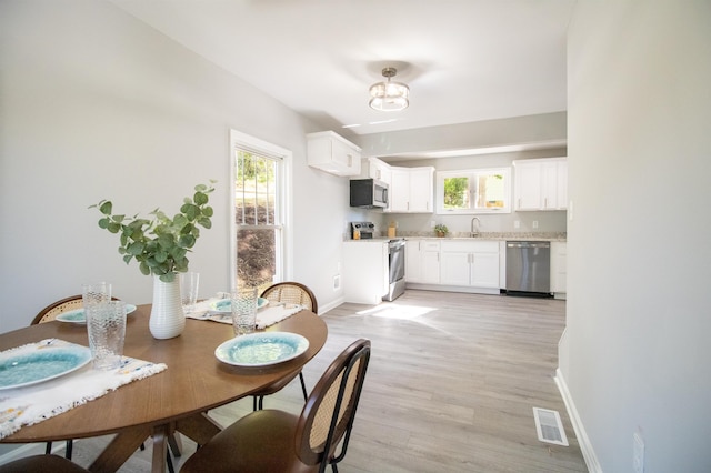 dining space with plenty of natural light, baseboards, and light wood-type flooring