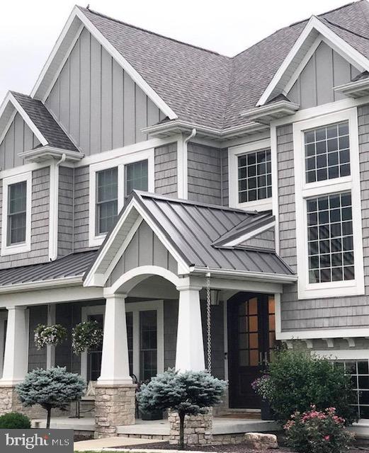 exterior space with board and batten siding, a standing seam roof, roof with shingles, and metal roof