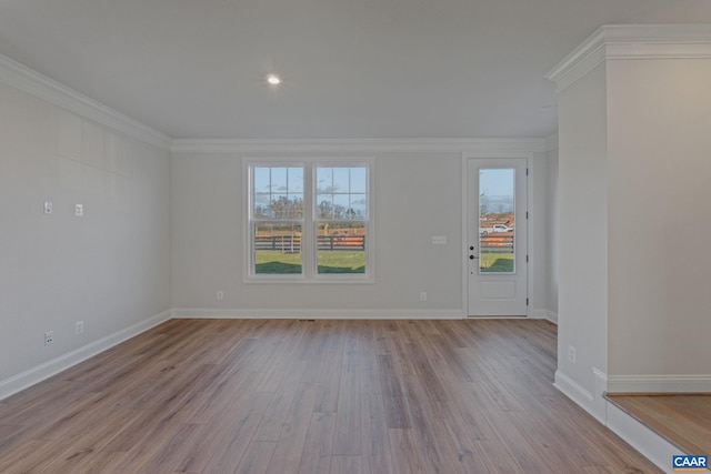 spare room with wood finished floors, baseboards, and ornamental molding