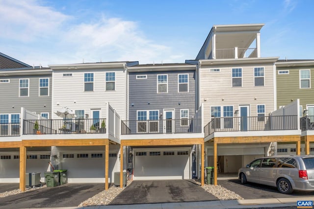 rear view of property featuring central AC unit, driveway, and a garage