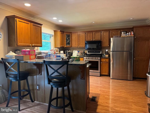 11068 Alum Springs Rd, Culpeper, VA 22701 - kitchen with stainless steel appliances, a peninsula, a kitchen bar, brown cabinetry, and light wood-style flooring