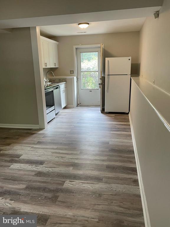 4504 Mine Rd, Fredericksburg, VA 22408 - kitchen featuring freestanding refrigerator, wood finished floors, white cabinetry, baseboards, and dishwasher