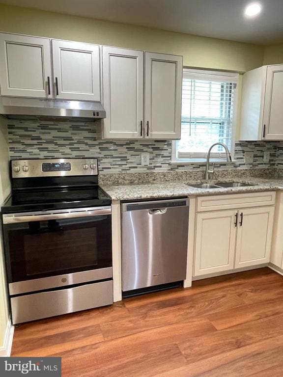 4504 Mine Rd, Fredericksburg, VA 22408 - kitchen featuring appliances with stainless steel finishes, a sink, under cabinet range hood, decorative backsplash, and light wood finished floors