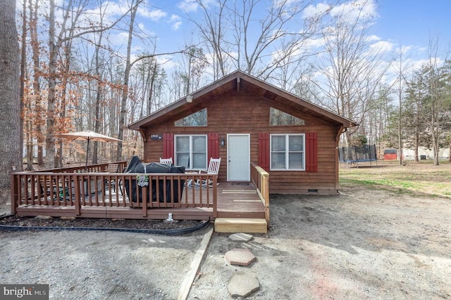 chalet / cabin with crawl space, a trampoline, and a deck