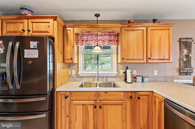 kitchen featuring light countertops, pendant lighting, a sink, and appliances with stainless steel finishes