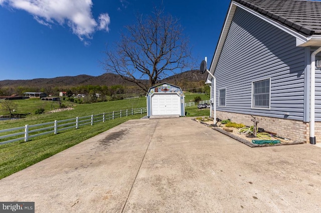 view of side of home with fence, an outbuilding, a lawn, a mountain view, and a garage