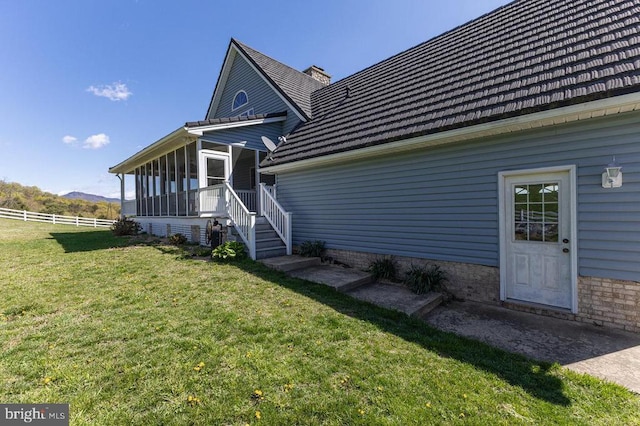 back of property with a sunroom, fence, a yard, and a mountain view