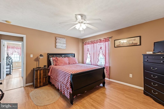 bedroom featuring ceiling fan, baseboards, a textured ceiling, and light wood finished floors