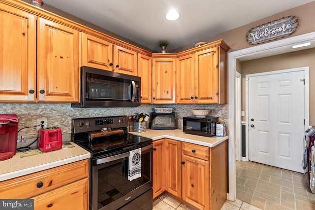 kitchen featuring black microwave, light countertops, decorative backsplash, and stainless steel range with electric stovetop