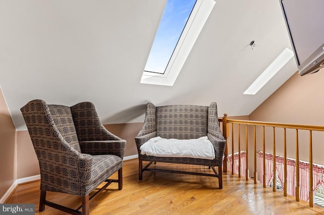 sitting room featuring vaulted ceiling with skylight and wood finished floors