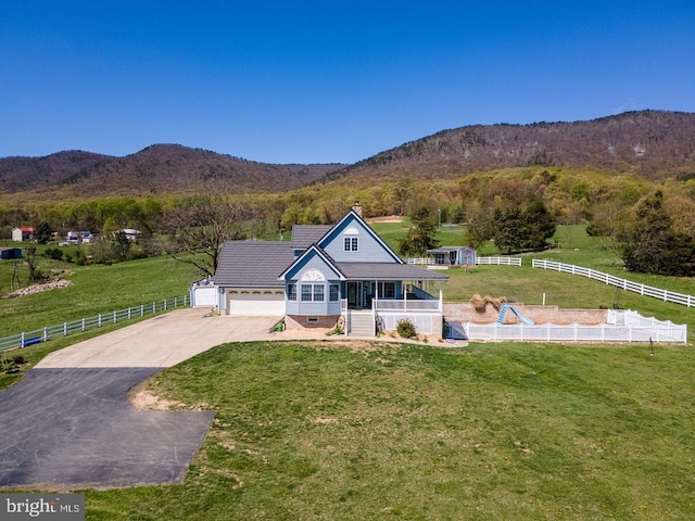 view of front of property with a front lawn, driveway, fence, and a mountain view