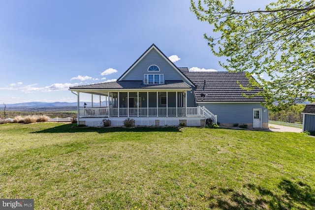 back of house with a sunroom, a yard, and a mountain view