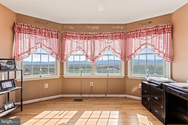 interior space featuring baseboards, light wood-style flooring, visible vents, and a wealth of natural light