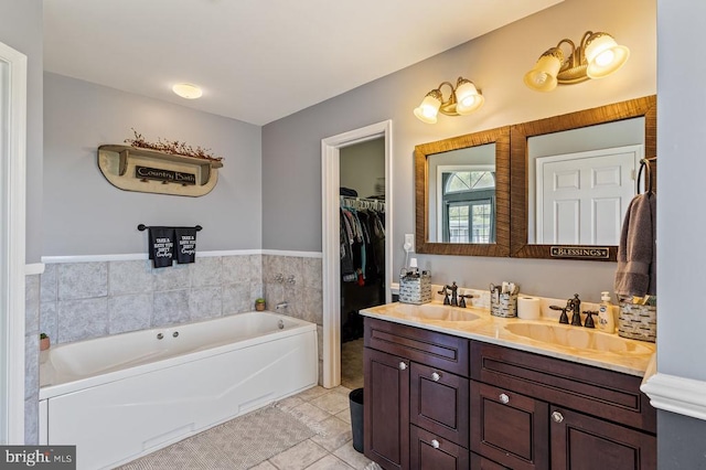 bathroom with double vanity, a garden tub, tile patterned floors, and a sink