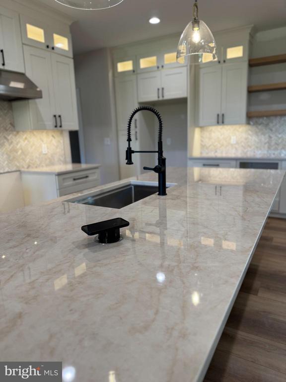 - kitchen featuring under cabinet range hood, decorative backsplash, decorative light fixtures, white cabinetry, and recessed lighting