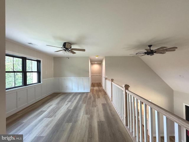  - unfurnished room with ceiling fan, wood finished floors, and wainscoting