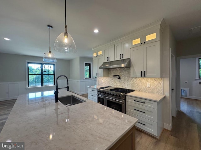  - kitchen with under cabinet range hood, double oven range, wood finished floors, a wainscoted wall, and recessed lighting