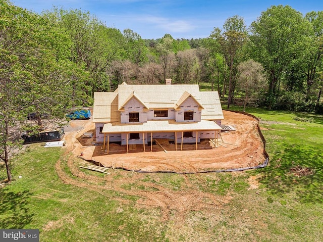  - back of house featuring a wooded view, a chimney, and a yard