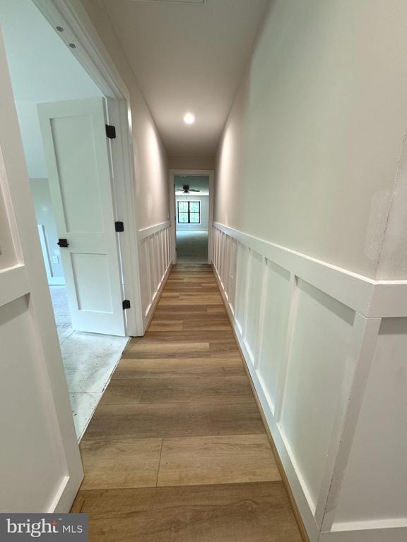  - hallway featuring wood finished floors, a wainscoted wall, and a decorative wall