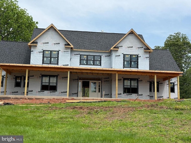  - rear view of house with covered porch, roof with shingles, and a lawn