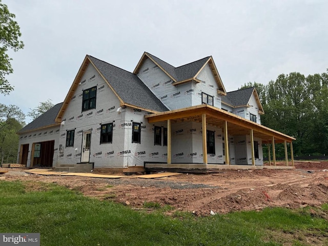  - back of house featuring a shingled roof and covered porch