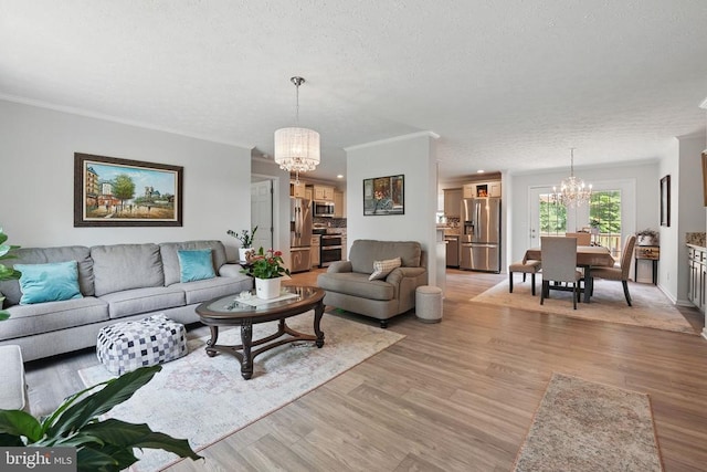  - living area featuring a chandelier, light wood-style floors, ornamental molding, and a textured ceiling